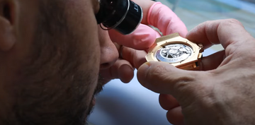a man looking at the back of a watch dial