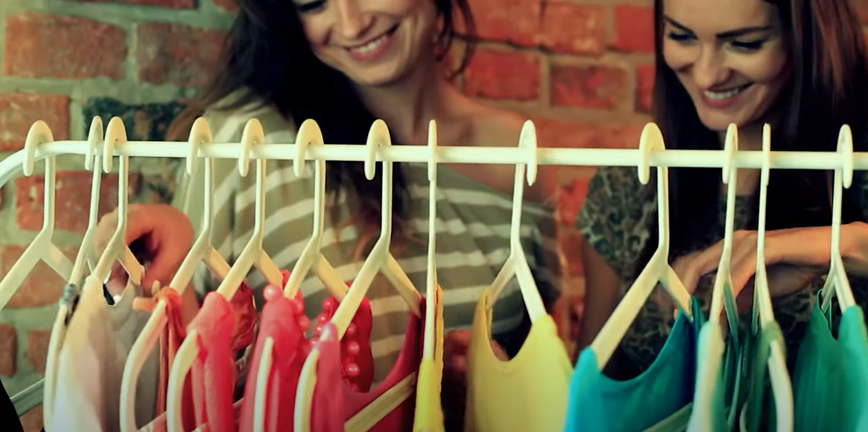 two women choosing colorful clothes on a rack