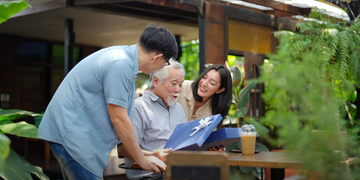 a man and a woman giving a gift to their aged dad