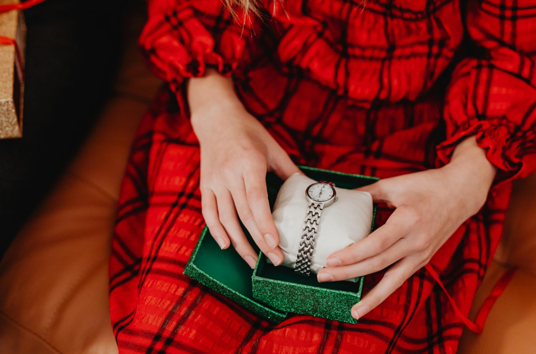 a woman holding a green box with silver wrist watch inside