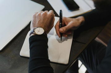 a man holding a pen while looking at his wristwatch 
